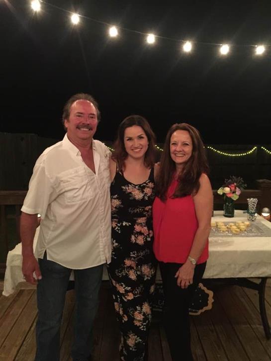 Three people enjoy their time together outdoors, surrounded by warm lights and joy.