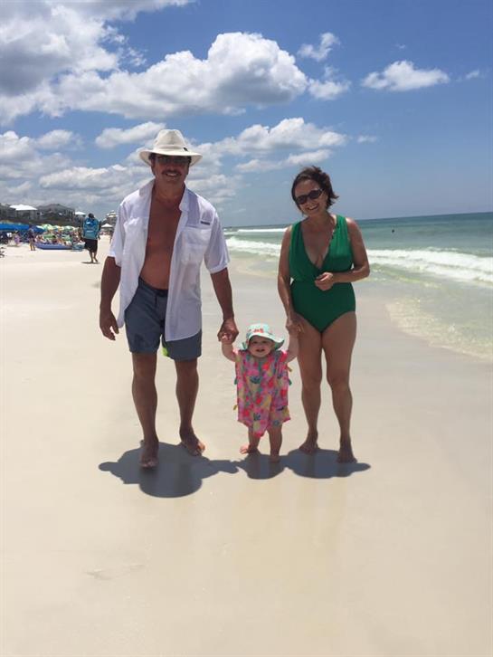 A family walks the sunny beach, sharing smiles and playful moments together.