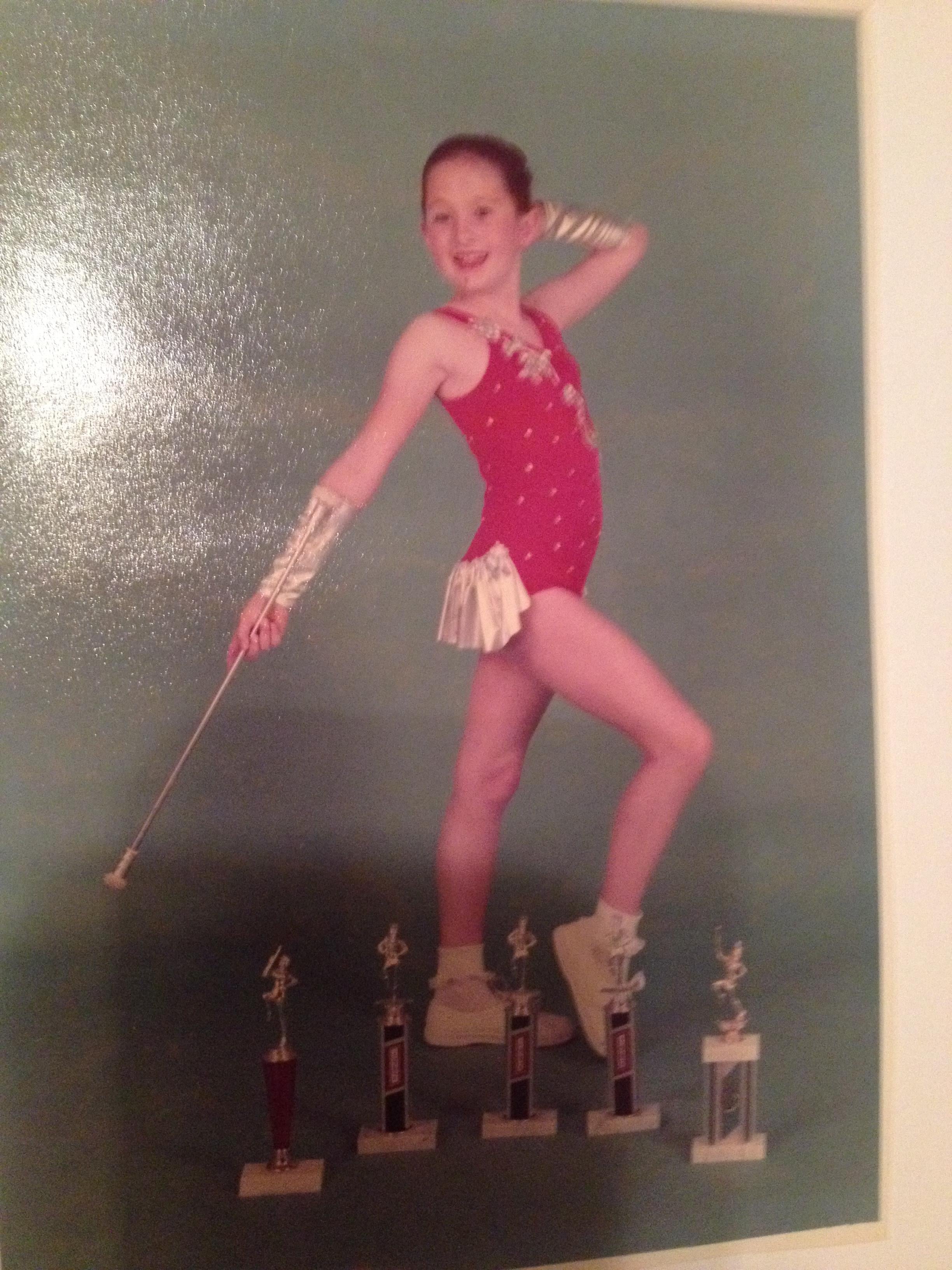 A girl in a red leotard holding a baton