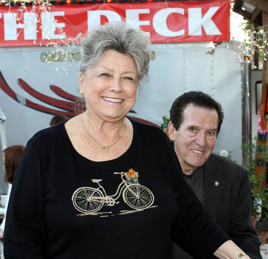 Two adults share a joyful moment at an outdoor gathering amid colorful decorations.