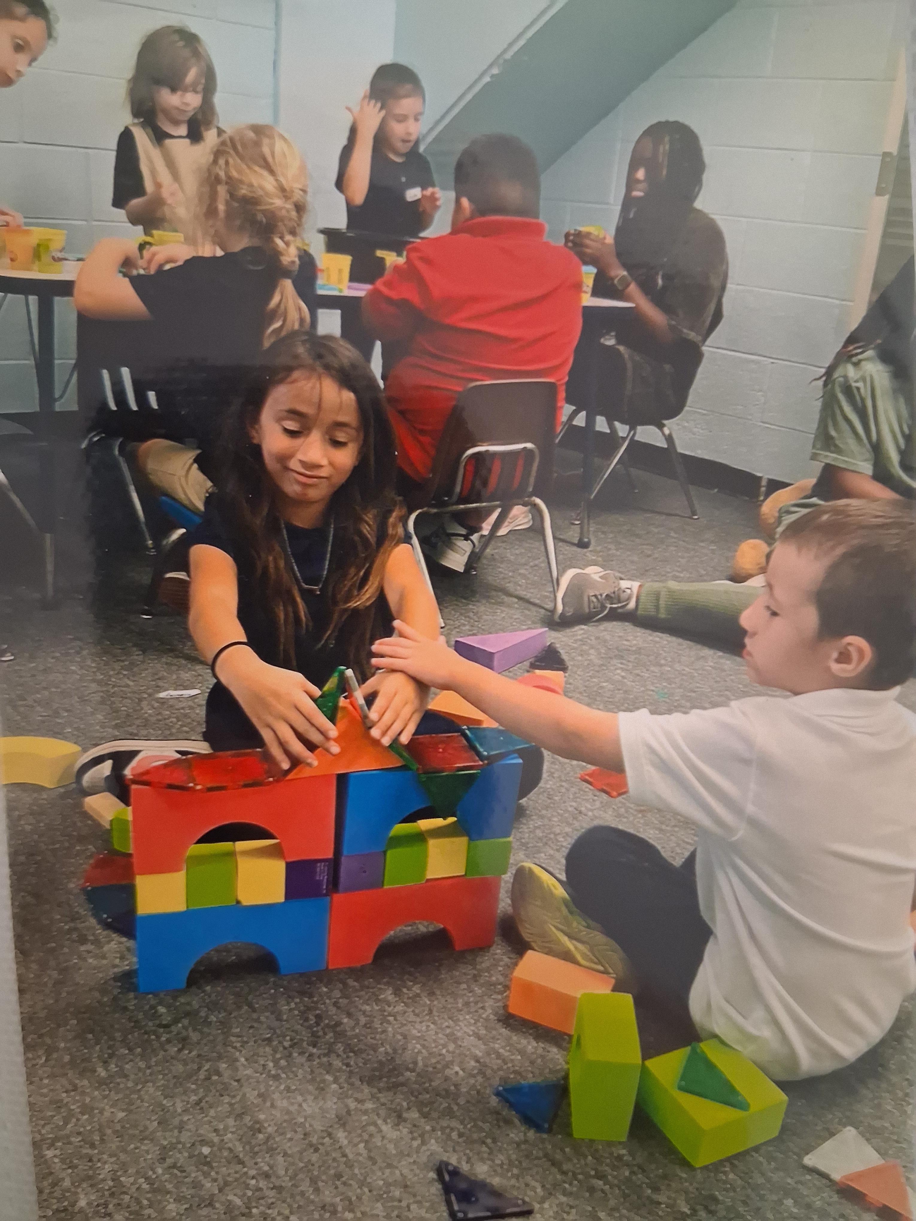 Kids are collaborating to build structures using vibrant blocks in a classroom setting.