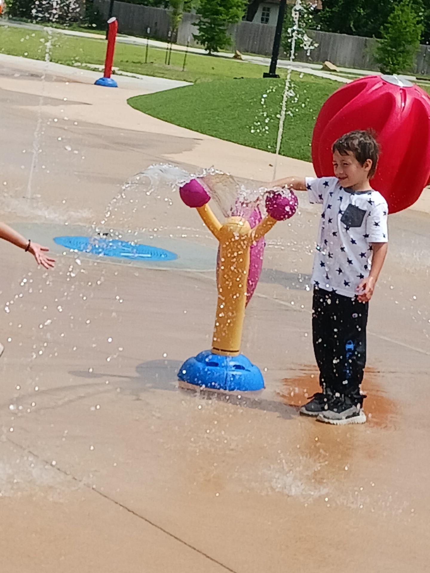 Kids enjoy a fun day at a splash pad, laughing and playing with water features on a warm day.