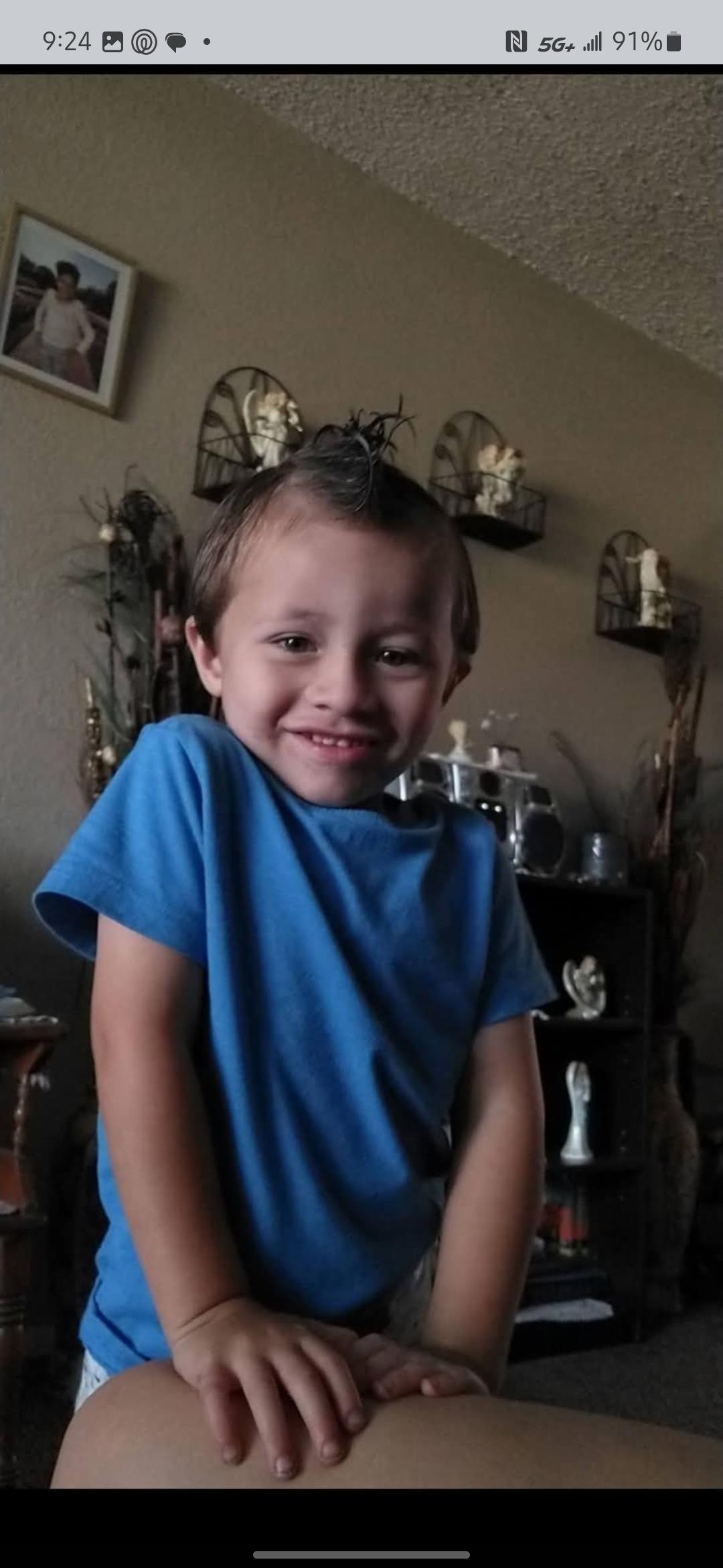 A cheerful young boy stands in a cozy living room, smiling happily while engaging in play.
