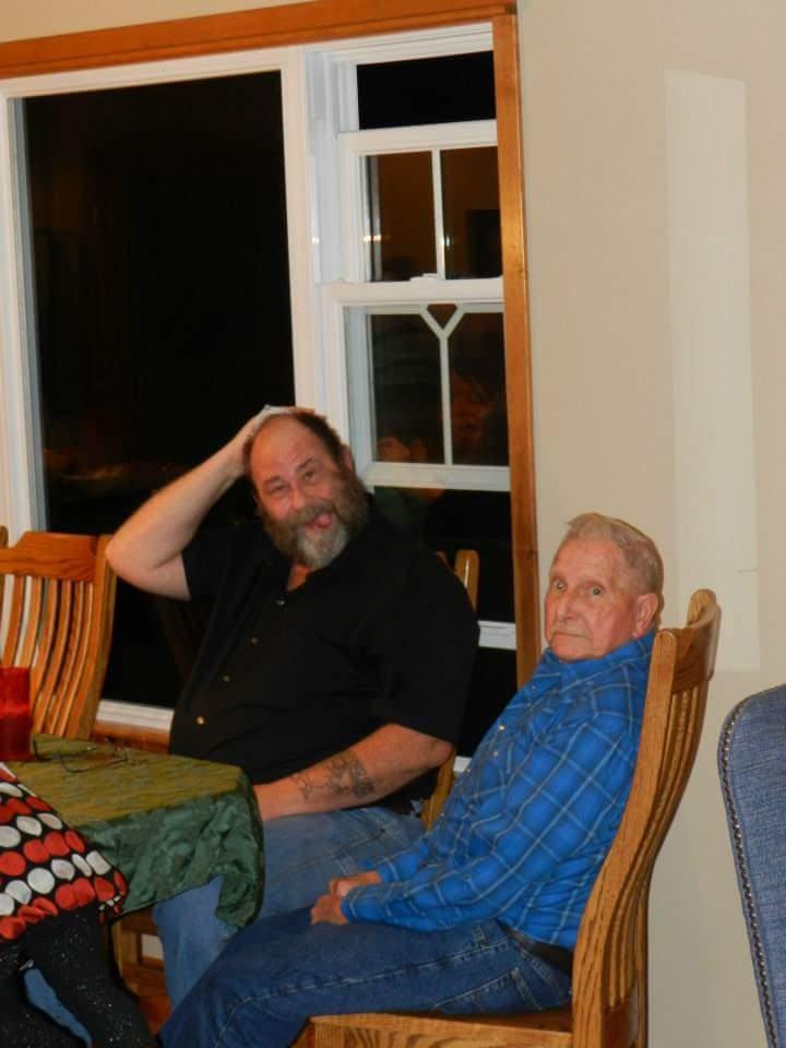 Two men relax in comfortable chairs, sharing stories during a pleasant evening indoors.