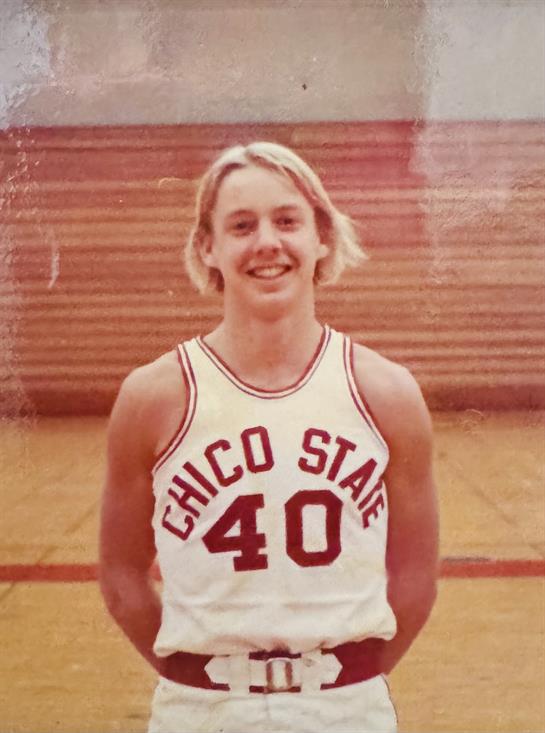 A young man stands in a basketball jersey featuring the number 40, smiling confidently in a gym.