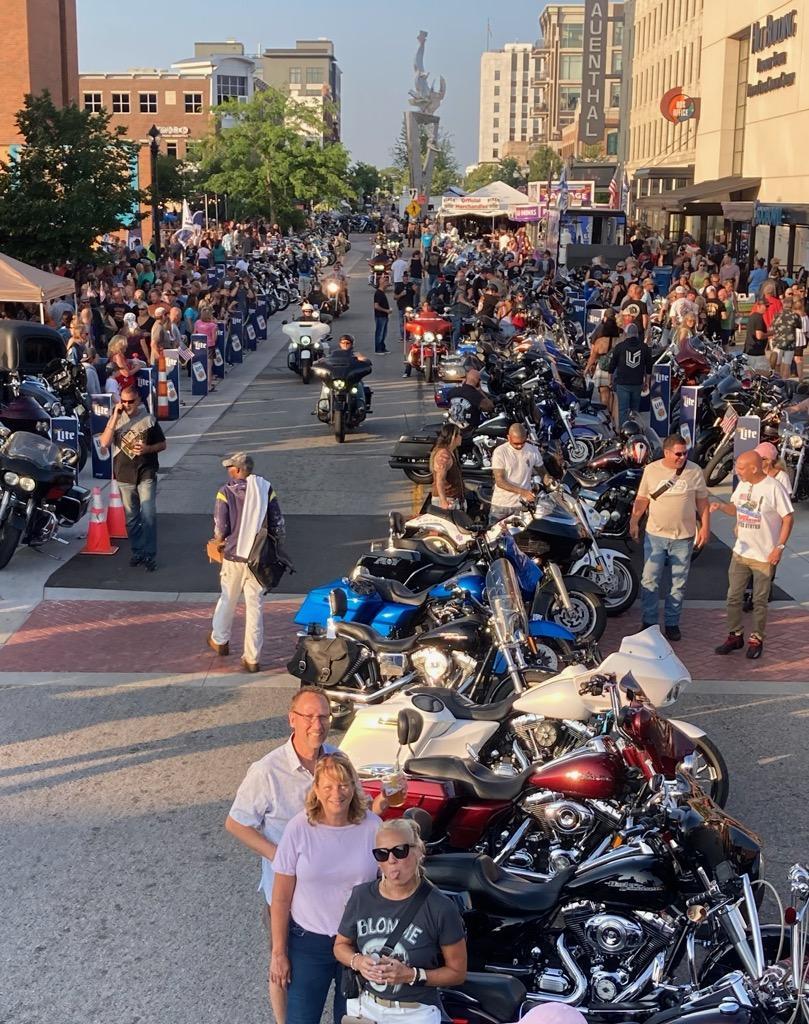 Enthusiastic riders gather at a vibrant downtown event featuring numerous motorcycles and onlookers.