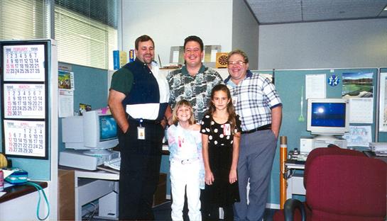 Friends and family gather in an office, smiling and enjoying a casual moment together.