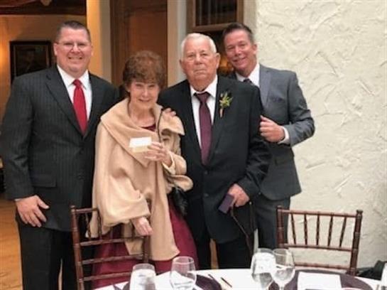 Four family members in formal attire pose at a stylish gathering.