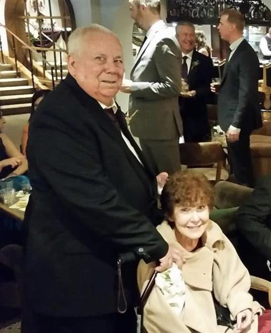 A joyful couple enjoys a lively gathering with friends and family in a sophisticated setting.