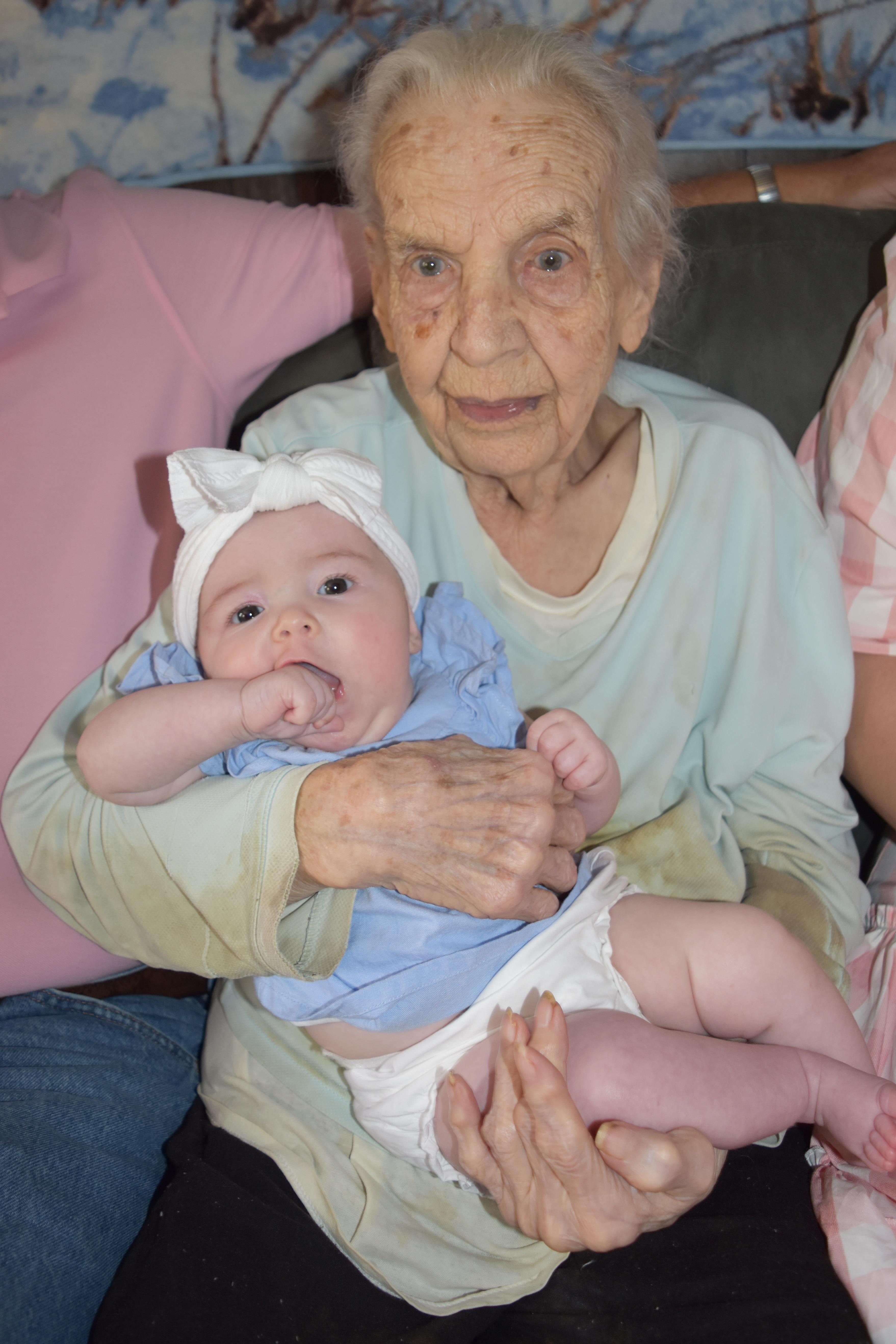 A grandmother lovingly holds her grandchild in a cozy family setting filled with warmth.