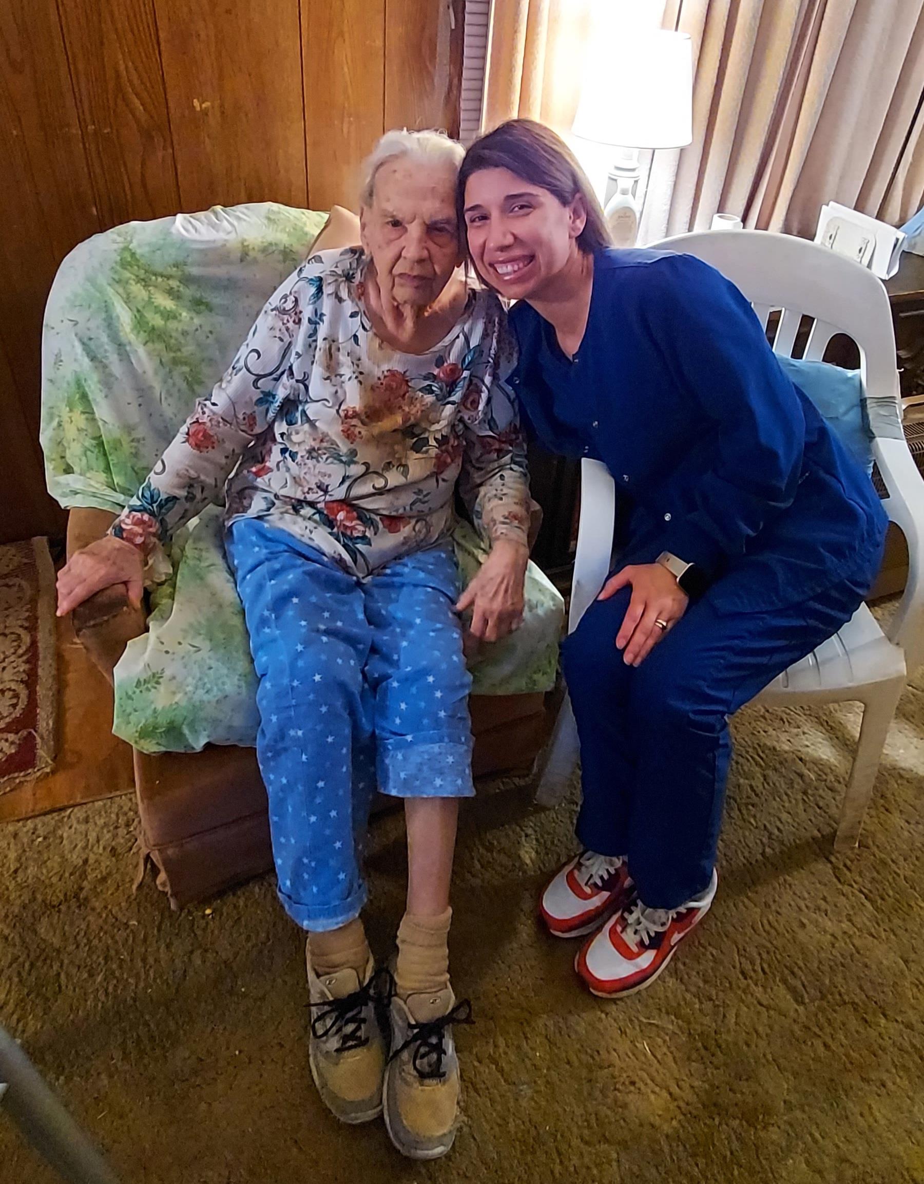 An elderly woman and her caregiver share a joyful moment in a warm living room.