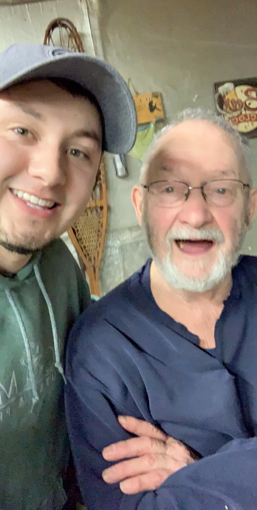 Two men share a joyful moment, smiling broadly while standing in a warm, inviting space.