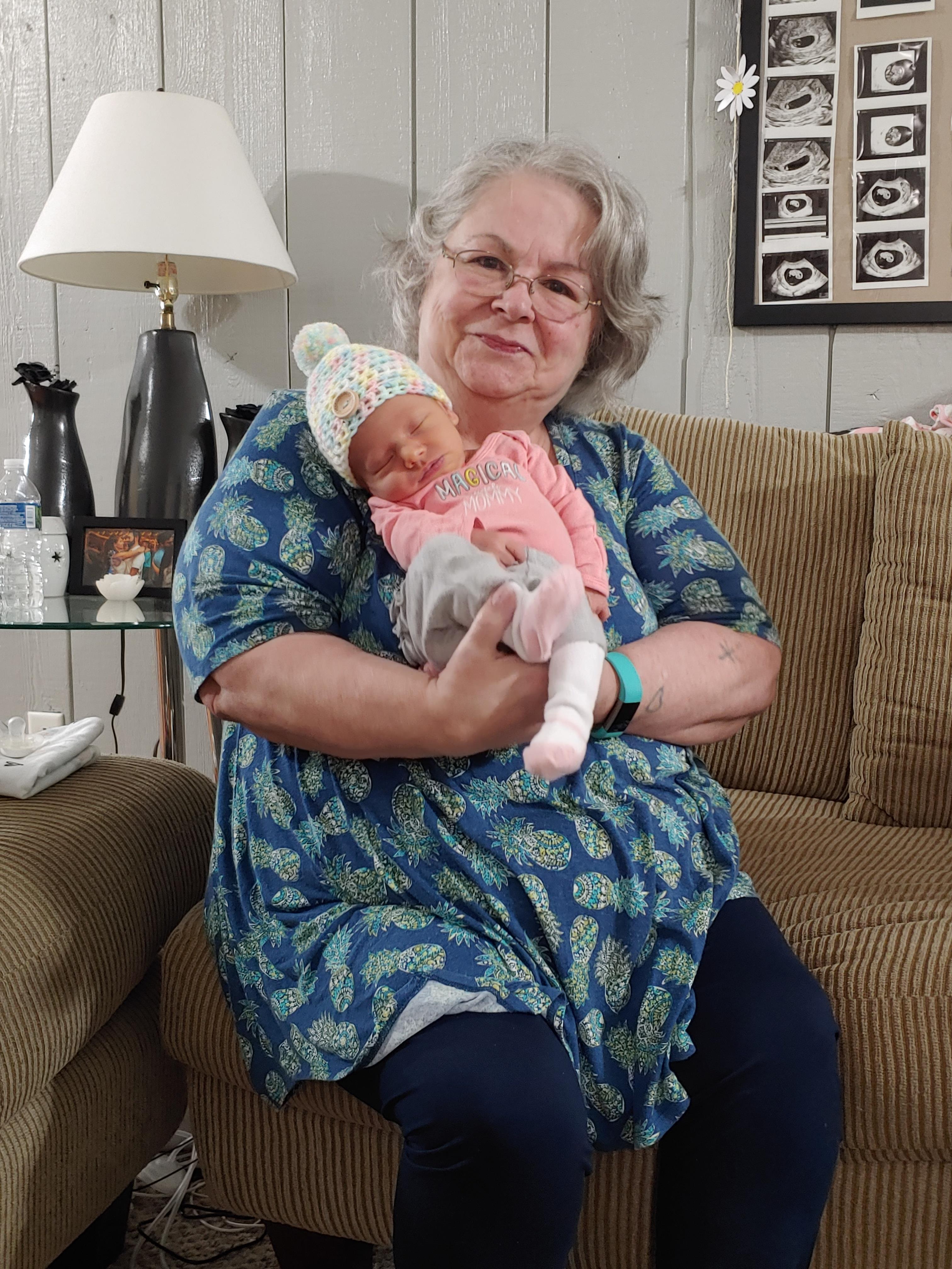 A grandmother lovingly cuddles her newborn grandchild, showcasing a warm family moment.