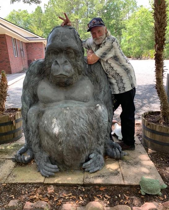 A man standing next to a statue of a gorilla
