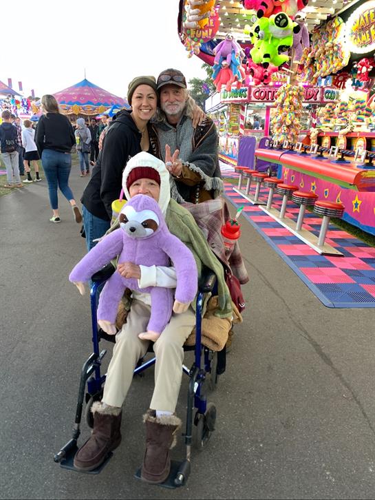 A man and woman in a wheelchair with a woman in a carnival