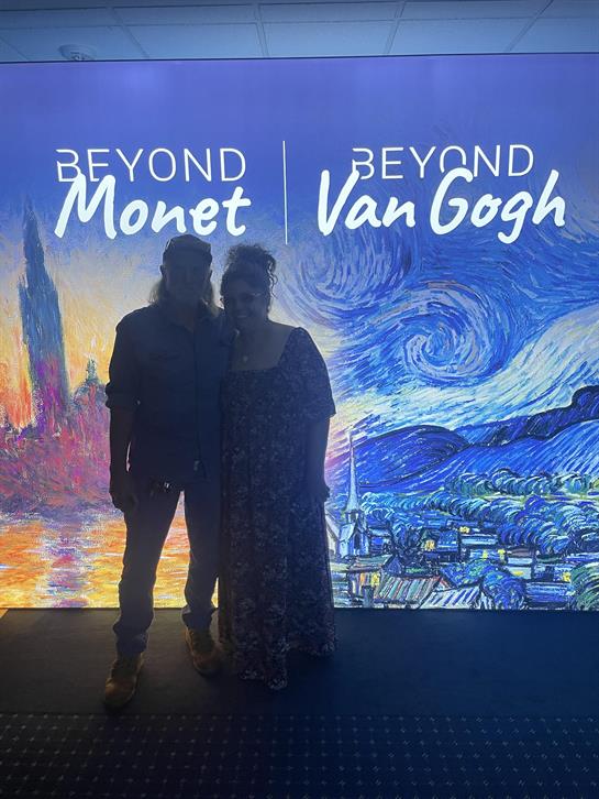 A man and woman standing in front of a painting