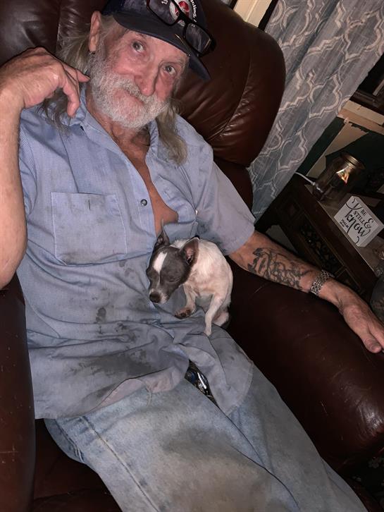 A man sitting on a leather chair with a dog