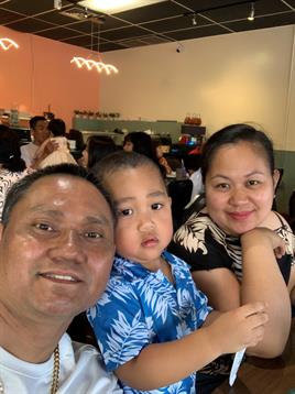 A family poses happily at a restaurant, sharing a meal and enjoying their time together.