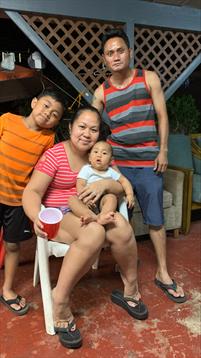 A family relaxes together on a patio, enjoying each other's company on a warm evening.