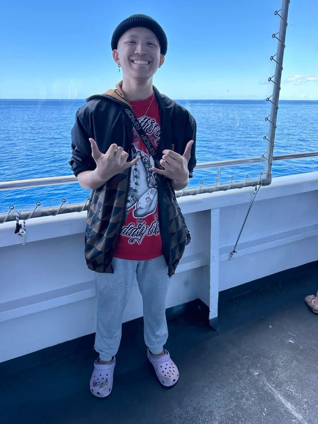 Young man wearing casual clothes and making fun hand gestures while on a boat