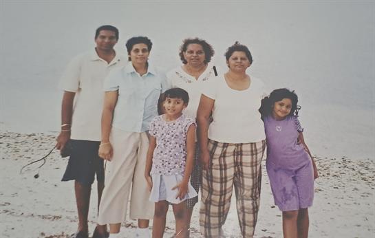 A close-knit family poses together on a beach, showcasing their happiness and connection.