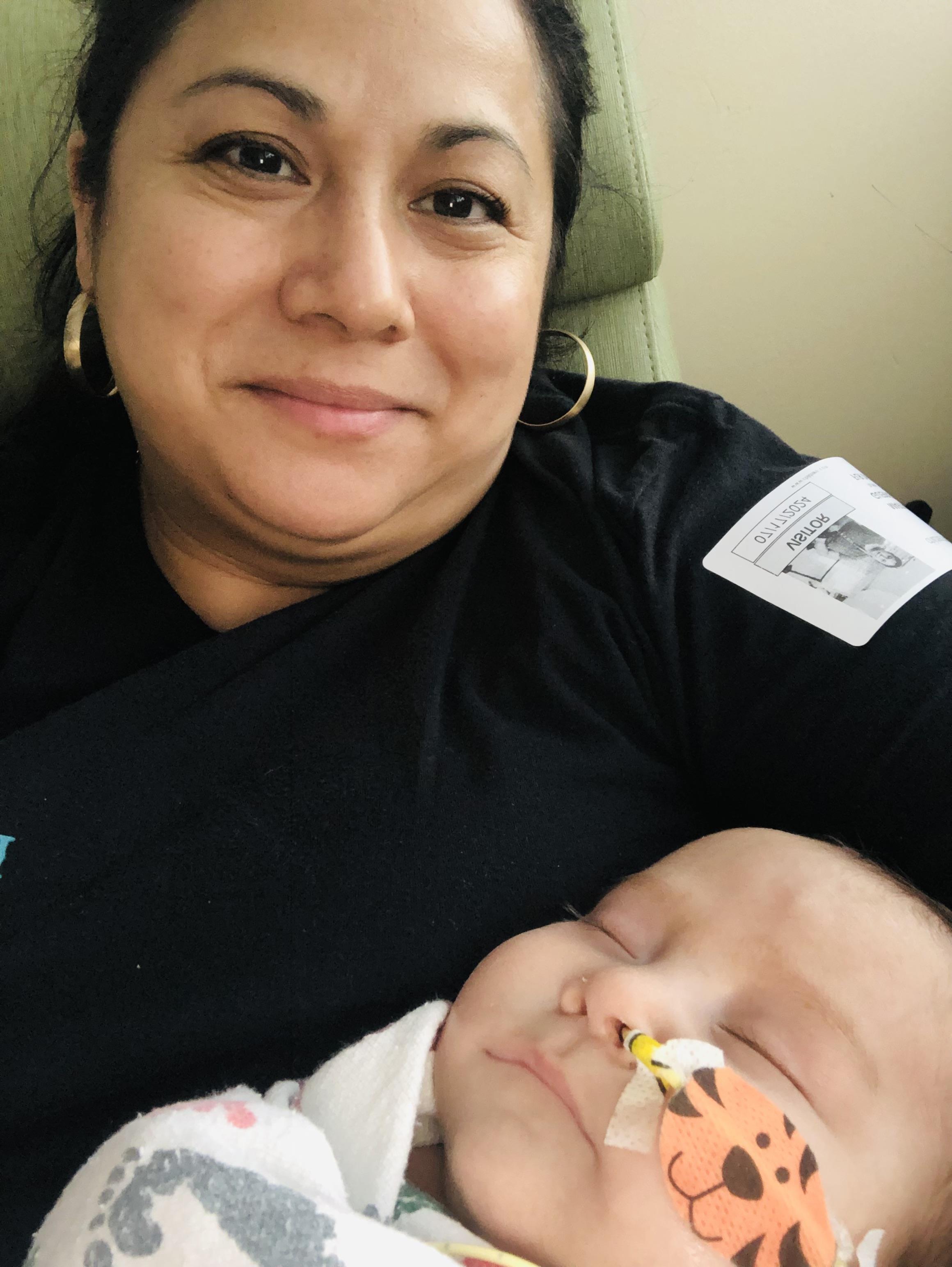 A mother lovingly holds her sleeping baby on her lap, radiating warmth and affection.