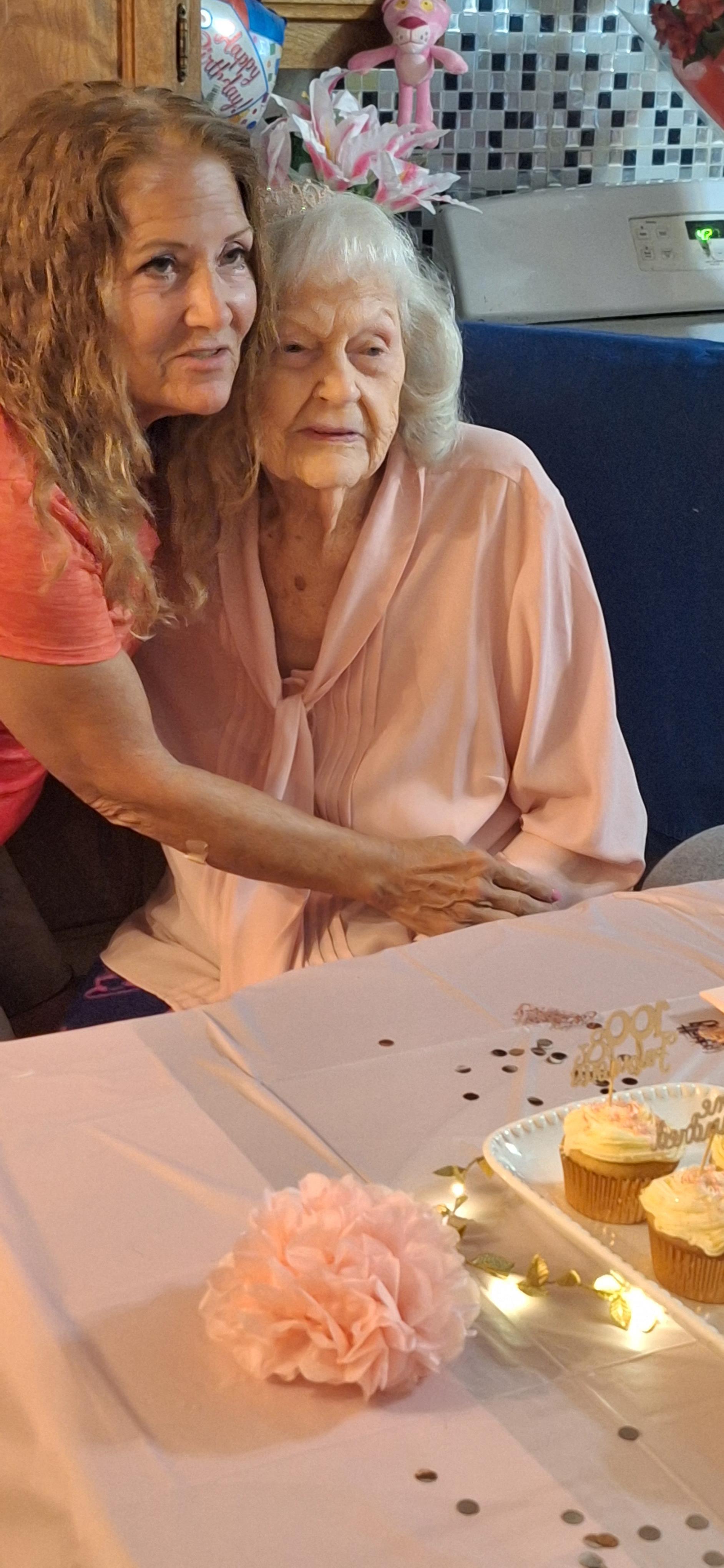 Two women share a joyful embrace while celebrating together at a table adorned with treats.