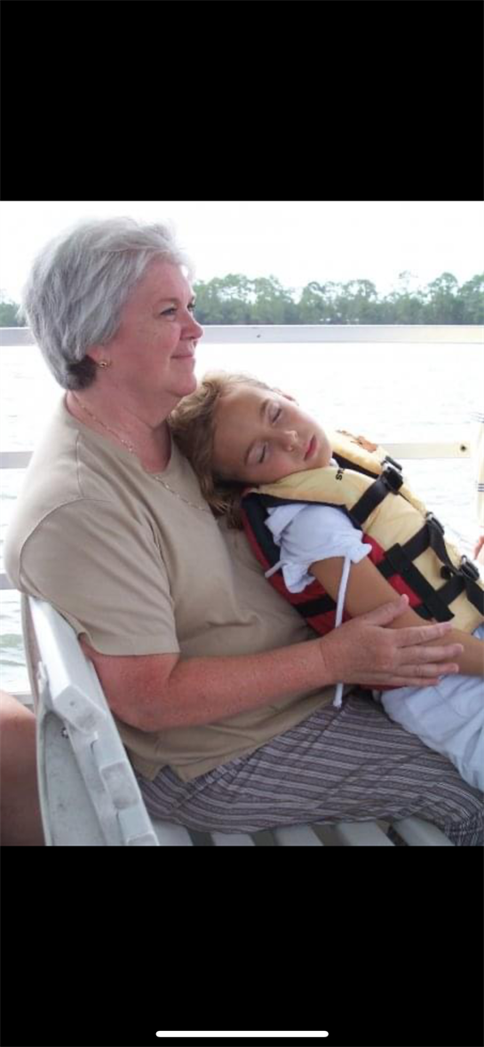 Grandmother holds her granddaughter as she peacefully sleeps in a life jacket on a boat.