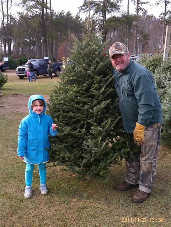 A man and child standing next to a christmas tree