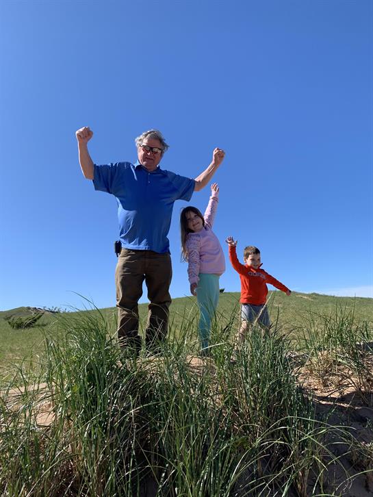 A man and two children standing in a grassy field