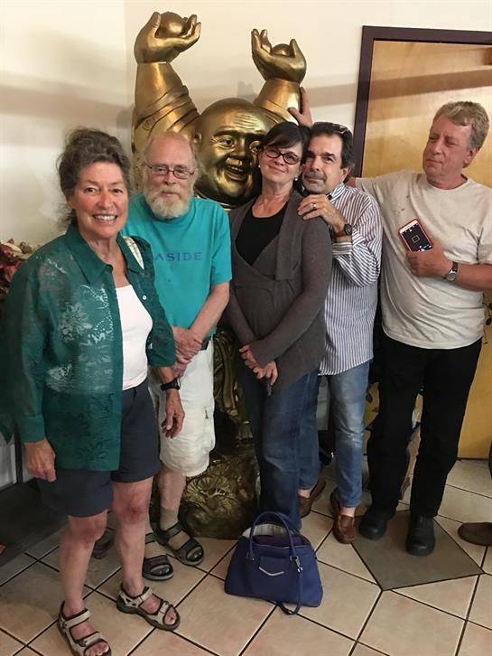 Five friends gather around a large golden statue smiling and enjoying their time together.