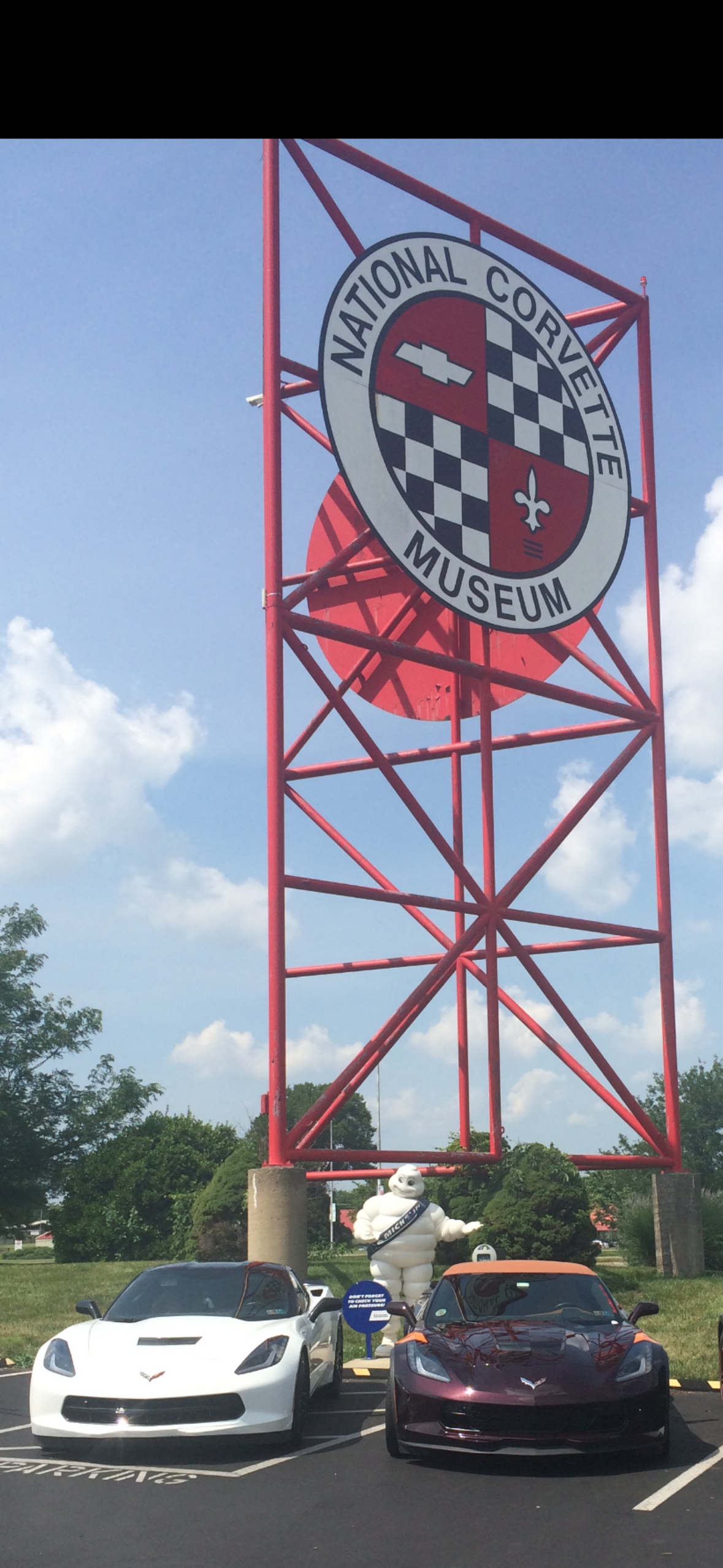 Iconic structure of the National Corvette Museum displayed with vintage cars under a clear sky.