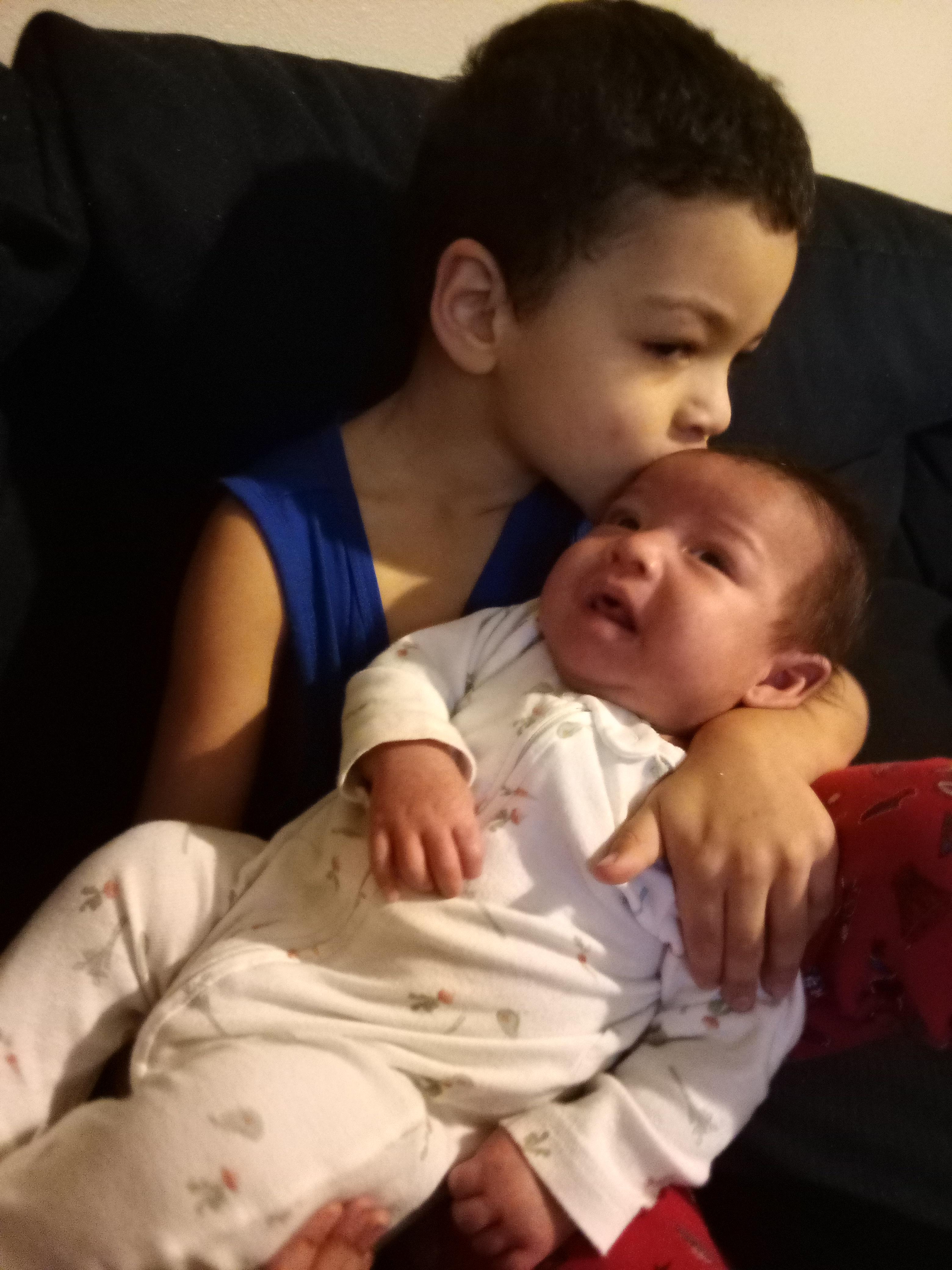 A boy kissing a baby
