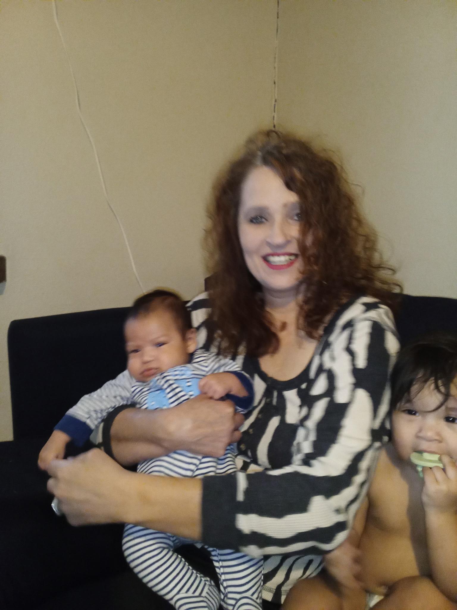 A woman holding a baby and smiling