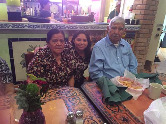 Three people are seated at a table, enjoying food in a vibrant restaurant setting.