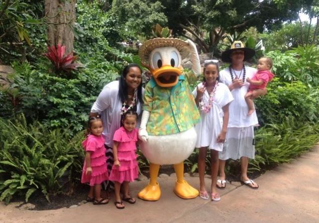 A family poses happily with a costumed character in a lush garden setting.