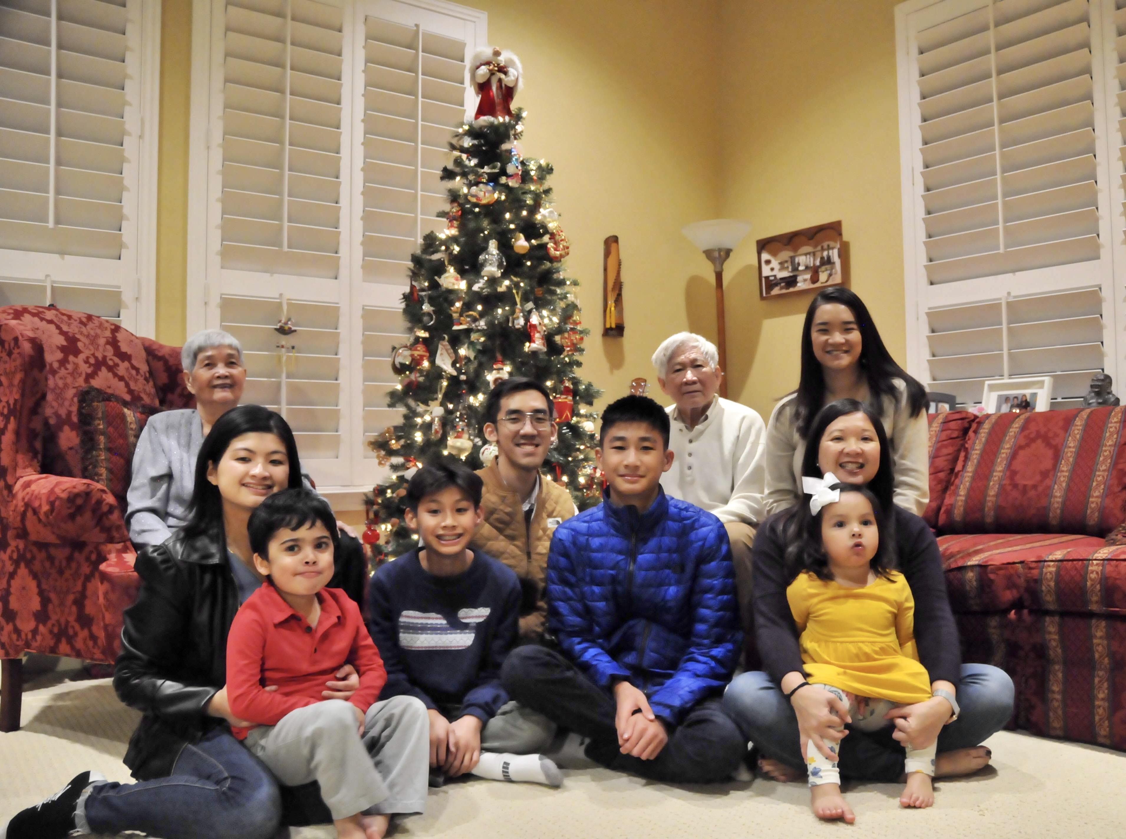 A family gathers around a beautifully decorated Christmas tree, sharing smiles and moments together.