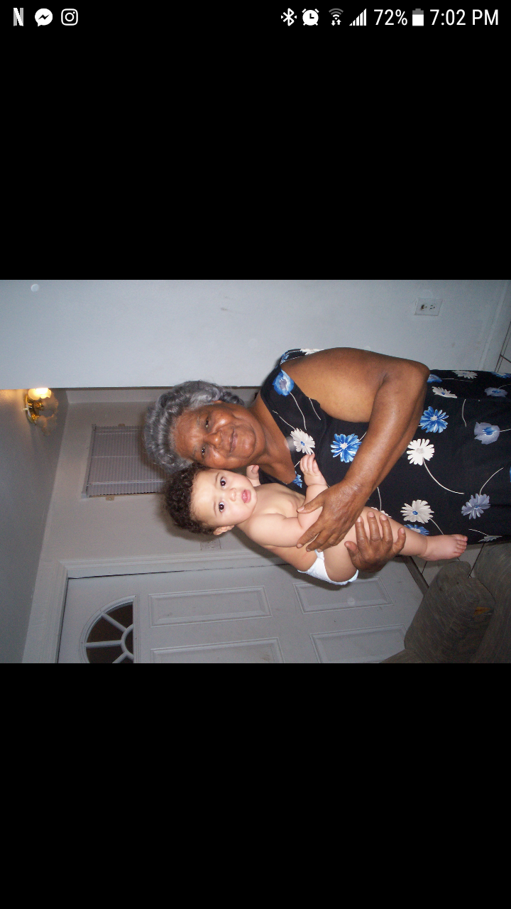 A loving grandmother cradles her grandchild in a warm home environment after sunset.