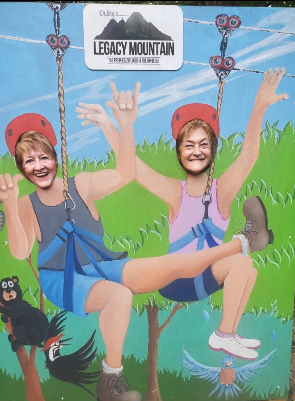 Two women with joyful expressions swing on a backdrop filled with greenery and animals.