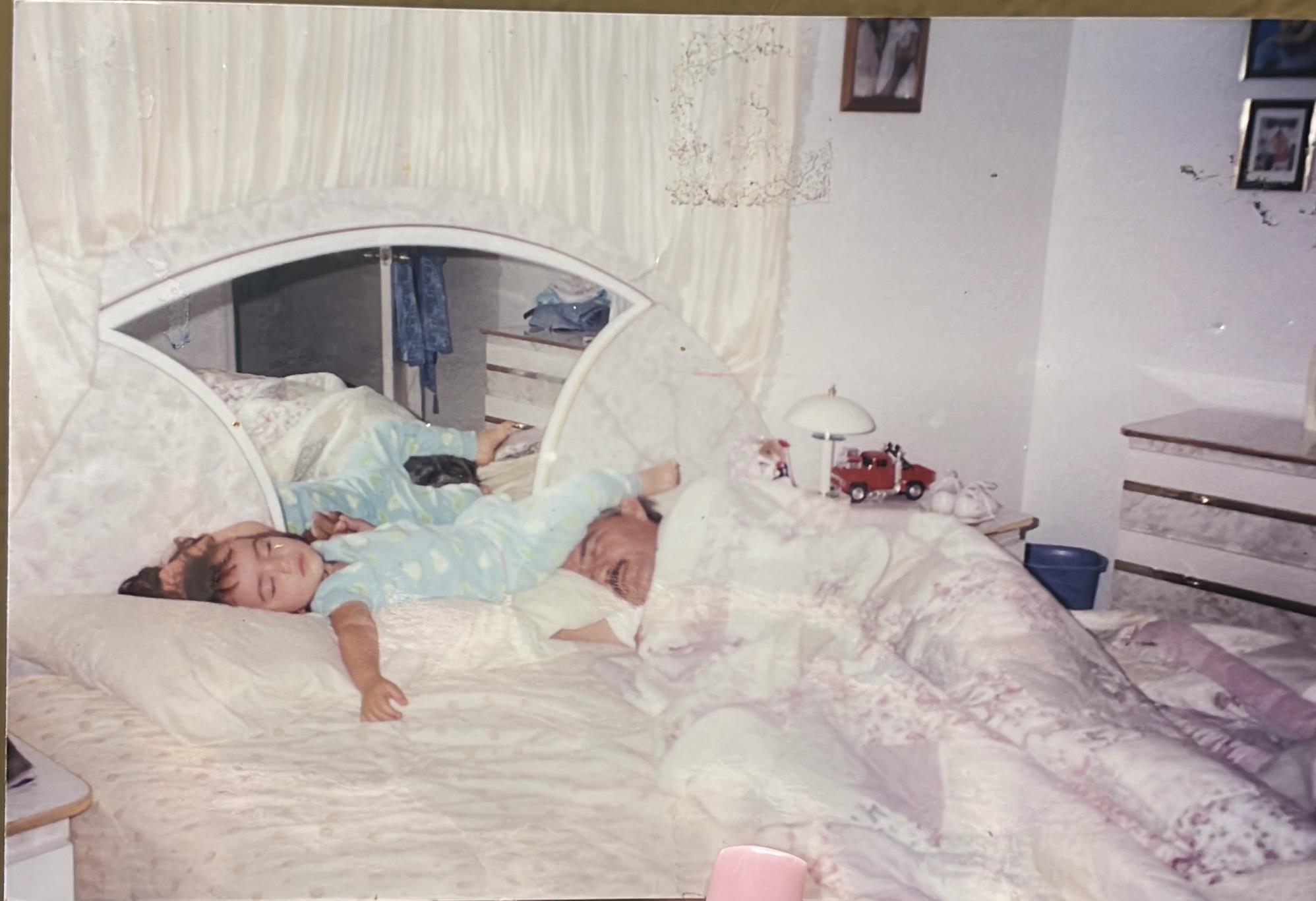 A child and parent share a serene sleep in a warm and inviting bedroom filled with soft textiles.