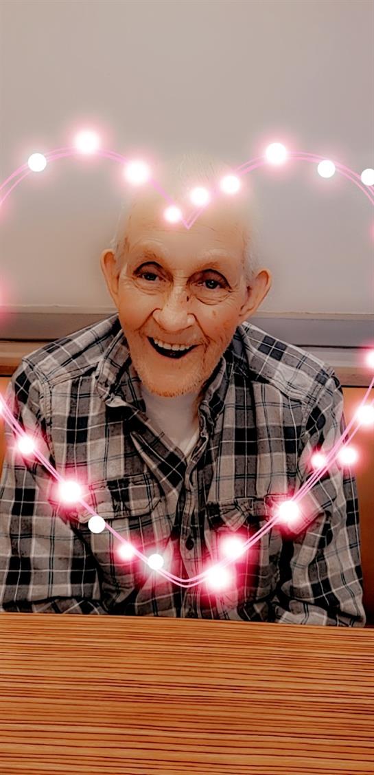 An old man smiling with a garland of lights