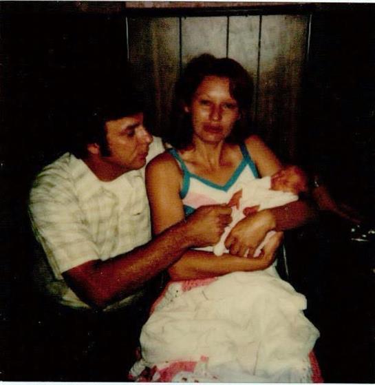 A couple cradles their newborn in a cozy room, expressing joy and affection in a timeless moment.