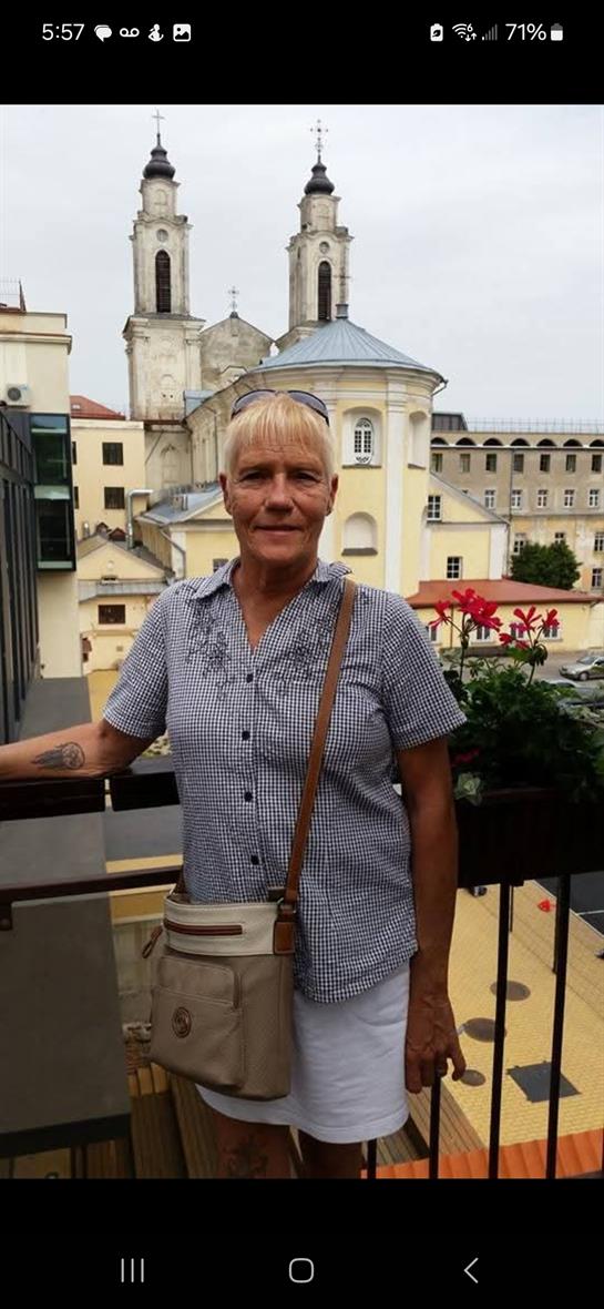A woman poses on a balcony with a stunning view of buildings and church towers.