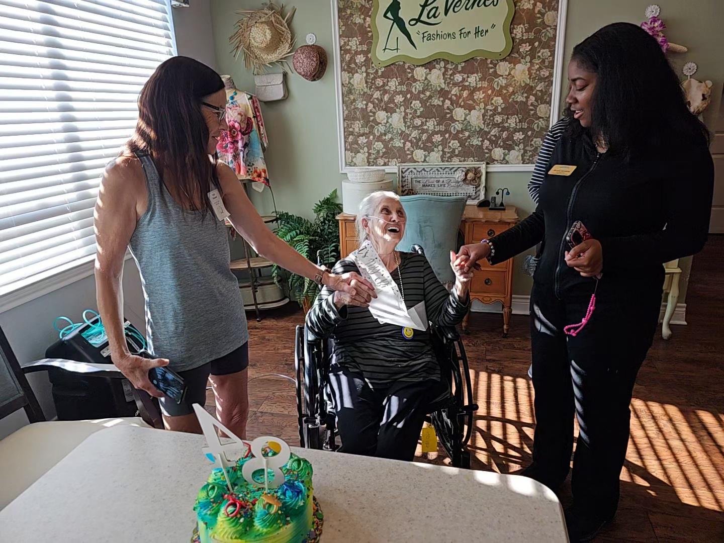Joyful gathering as family members celebrate a birthday with cake and laughter in a care facility.