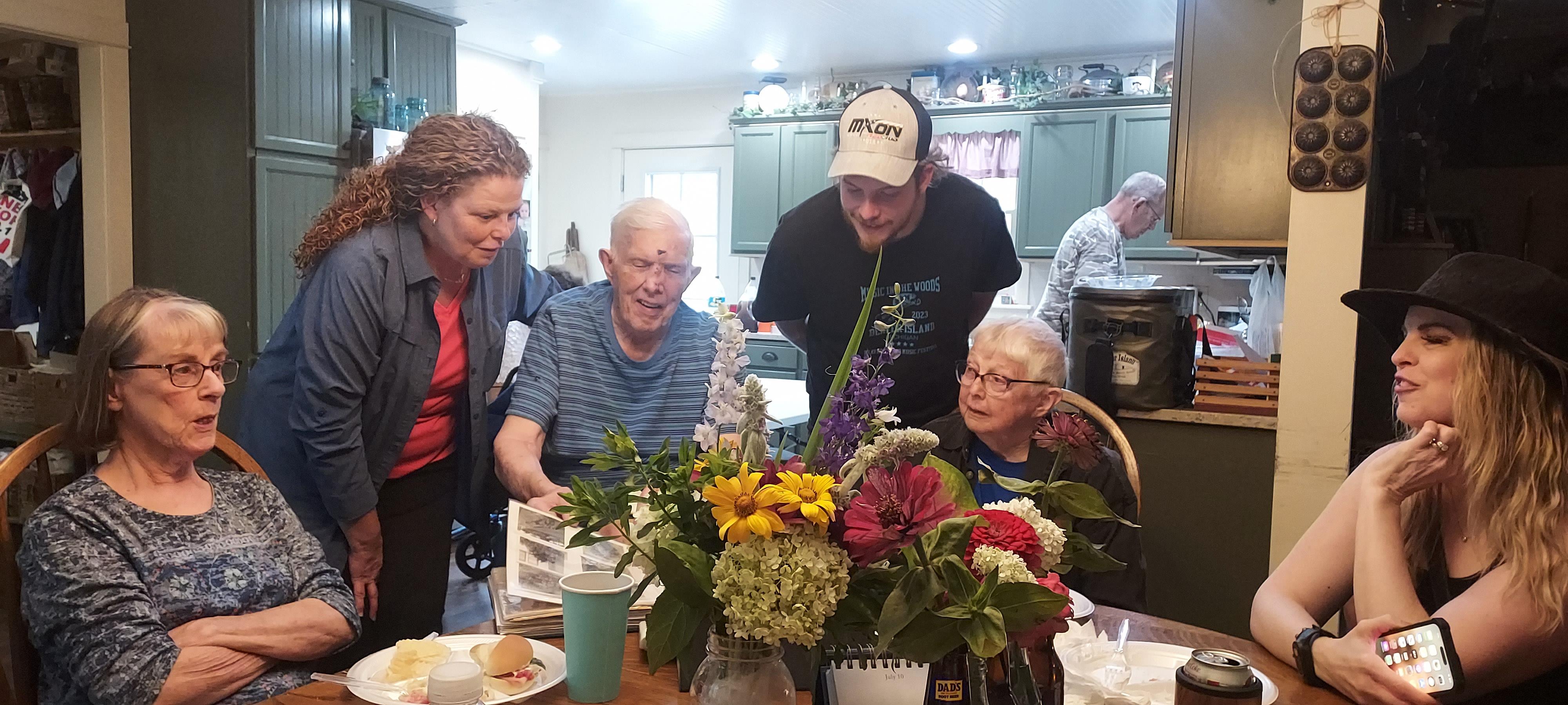 Six individuals engaged in a lively discussion while sharing a meal in a warm environment.