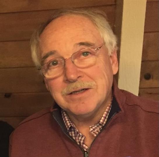 An elderly man enjoys a cheerful moment with friends in a warm, wooden setting.