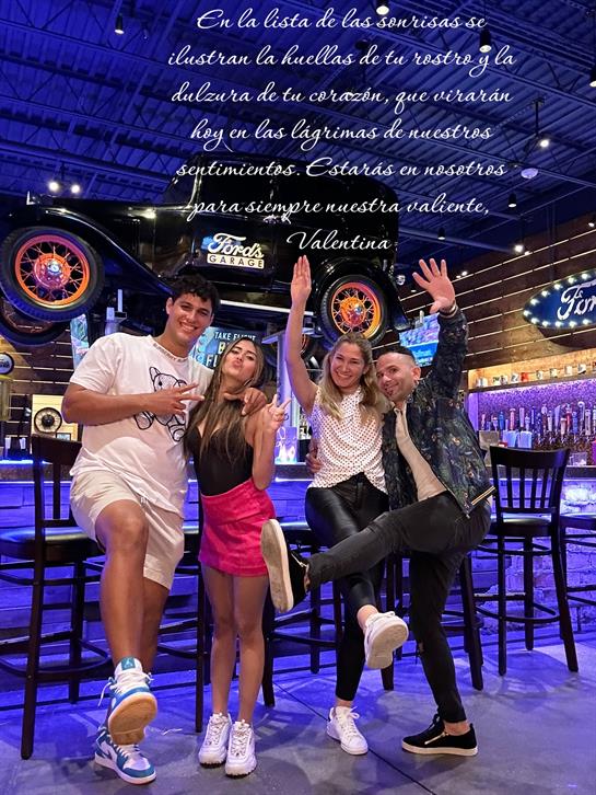 Four friends enjoy a fun evening, striking playful poses in a vibrant setting at night.