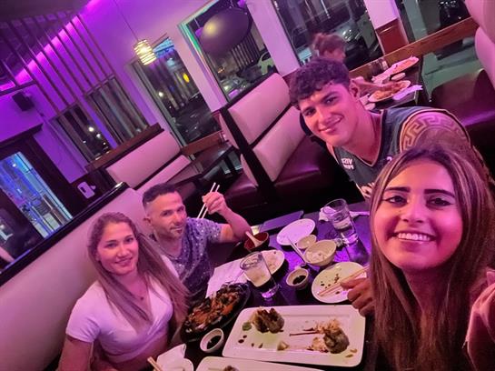 Friends gather around a table filled with food, laughing and enjoying their evening meal.