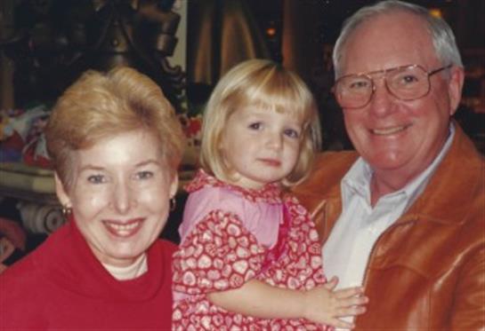 Grandparents joyfully hold their granddaughter in a warm and welcoming indoor environment.