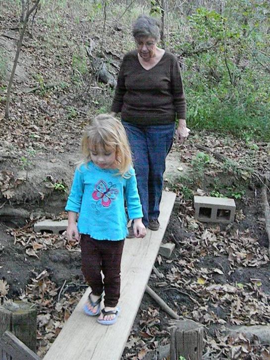 A woman walking with a child on a log